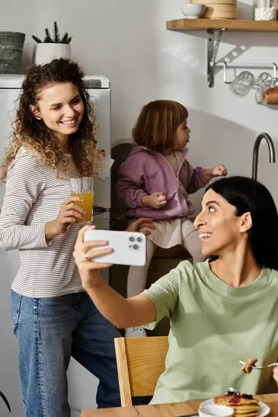 Deux femmes profitent d'un moment de joie dans leur appartement contemporain pendant que leur fille joue. — Photo de stock