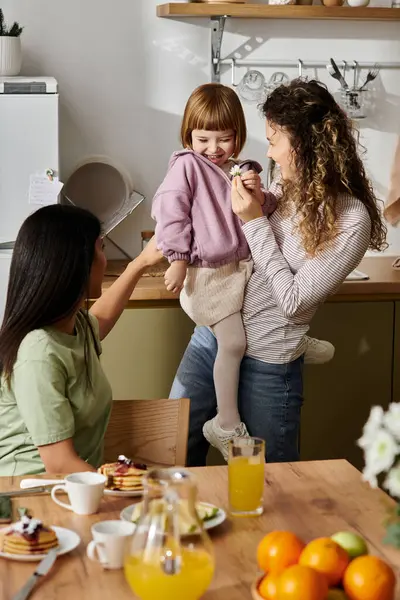 Two women share a delightful morning with their daughter in a stylish kitchen. — Stock Photo