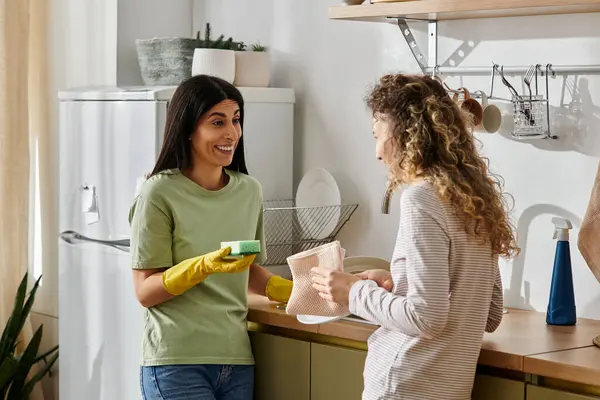 Two happy women engage in house chores, sharing smiles in their cozy apartment together. — Stock Photo