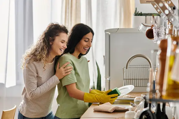 Felice coppia lesbica condivide risate come fanno piatti in una casa accogliente ed elegante. — Foto stock