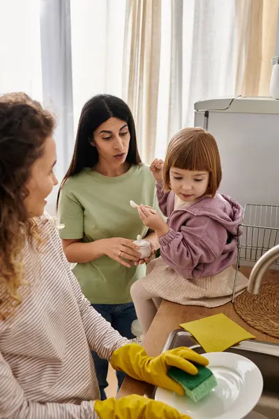 Zwei Frauen verbinden sich bei häuslichen Aktivitäten mit ihrer fröhlichen Tochter in einer lebendigen Umgebung. — Stockfoto