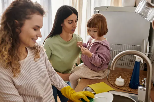 Two women are joyfully engaging with their daughter in a cozy apartment, sharing love and laughter. — Stock Photo