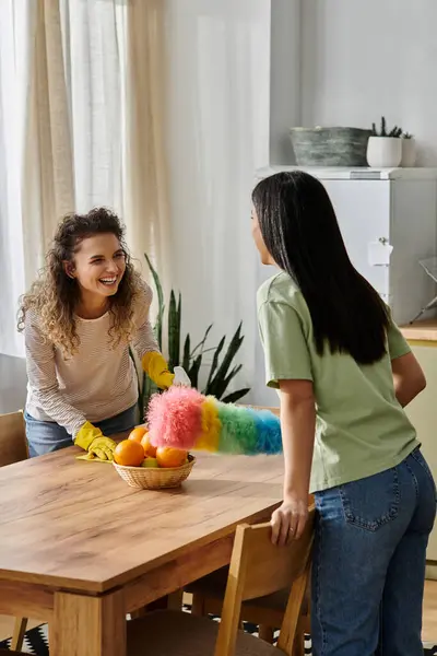 Zwei fröhliche Frauen teilen sich einen Moment, während sie ihre einladende Wohnung putzen und einander anlächeln. — Stockfoto
