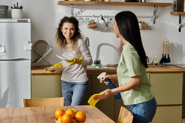 Zwei fröhliche Frauen teilen sich Lächeln und Aufgaben, strahlen Liebe aus, während sie ihr stilvolles Zuhause aufräumen. — Stockfoto