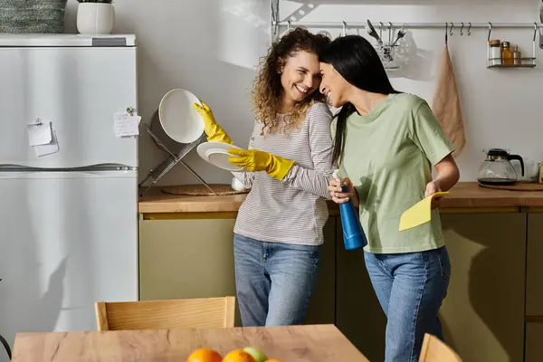 Zwei lesbische Frauen lächeln und genießen einen verspielten Moment, während sie ihr stilvolles Zuhause aufräumen. — Stockfoto