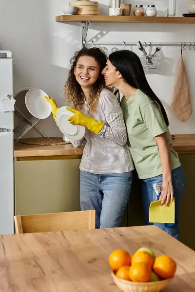 Zwei glückliche Frauen genießen einen verspielten Moment bei der Hausarbeit in ihrem stilvollen Zuhause. — Stockfoto