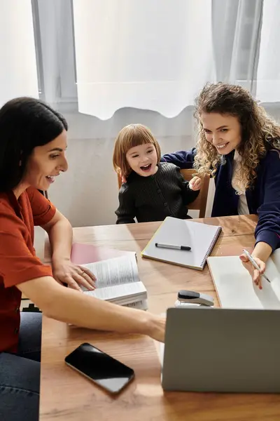 Two women and their daughter enjoy quality time together while studying at home. — Stock Photo