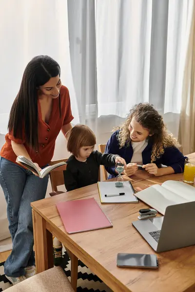 A joyful family moment as two mothers support their daughter in her creative activities. — Stock Photo