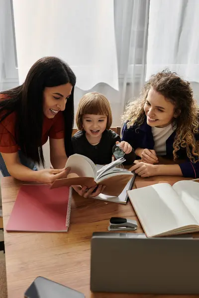 Two loving mothers share laughter with their daughter while reading together at home. — Stock Photo