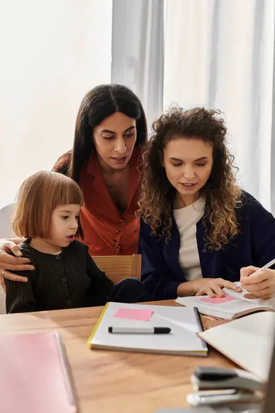 Due donne e la loro figlia collaborano a un progetto nel loro elegante appartamento. — Foto stock