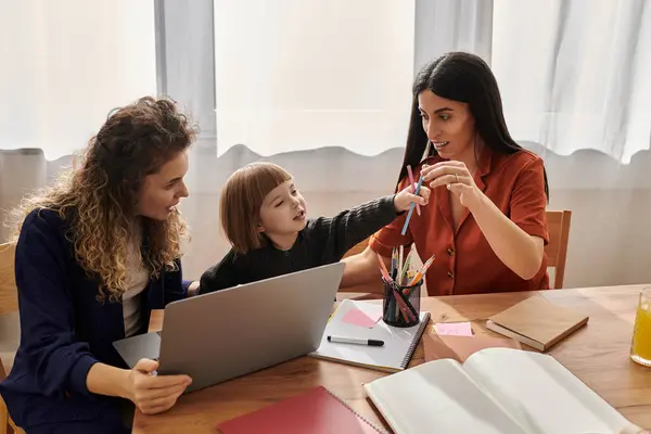 Dos mujeres comparten un momento de alegría con su hija mientras se dedican a actividades creativas en casa. — Stock Photo