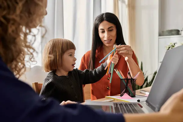 Two loving mothers engage their daughter in a colorful crafting activity indoors. — Stock Photo