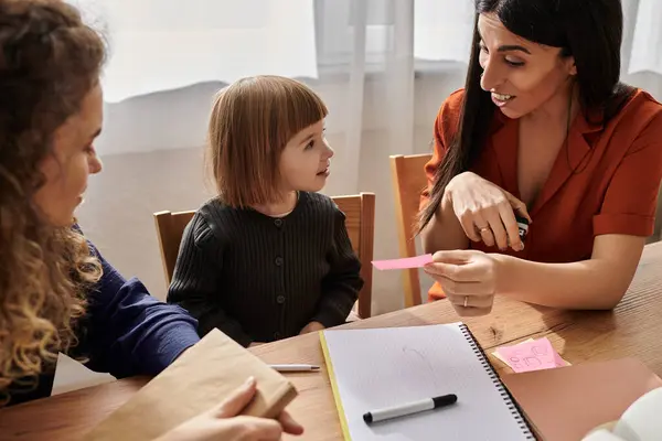 Due madri si impegnano con la figlia mentre si godono attività creative a casa. — Foto stock