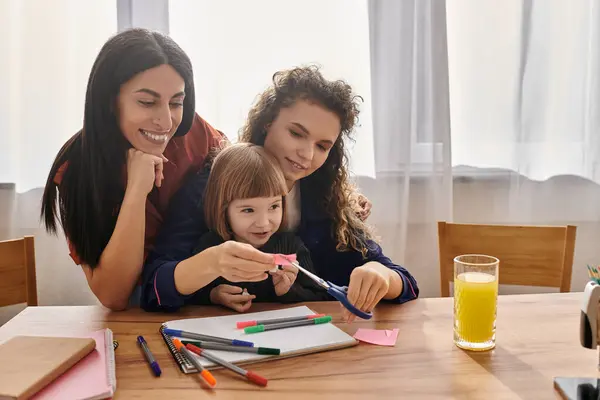 Due donne condividono un momento gioioso con la figlia mentre realizzano creazioni colorate nella loro casa. — Foto stock