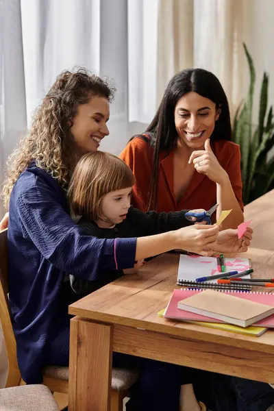 Two women and their daughter share smiles while doing creative activities in their modern apartment. — Stock Photo