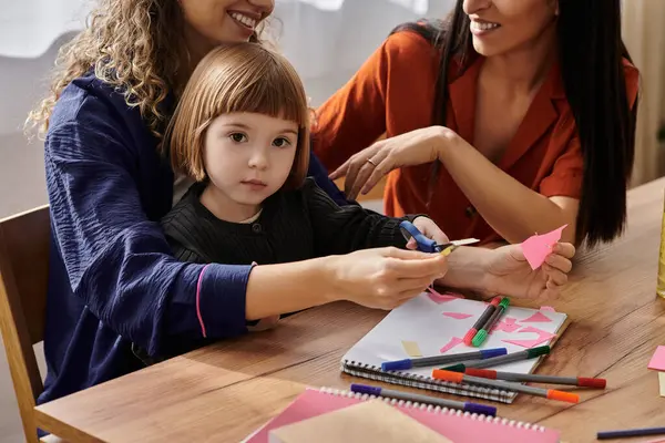 Two women enjoy quality time with their daughter, crafting colorful shapes in their bright home. — Stock Photo