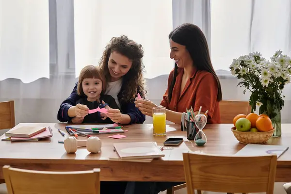 Two women share a joyful crafting moment with their young daughter in a bright apartment. — Stock Photo