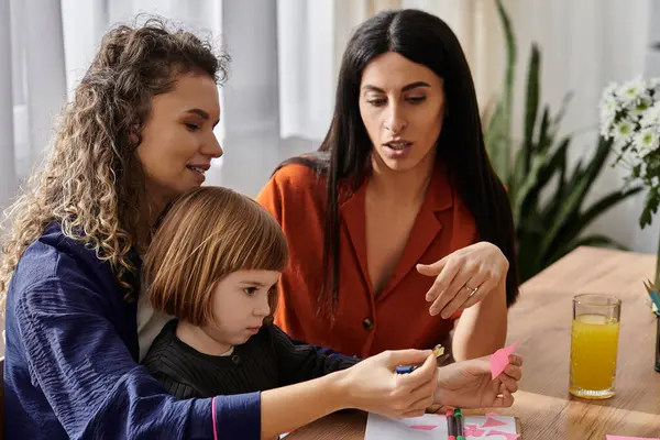 Two loving women engage creatively with their young daughter at home, highlighting family bonding. — Stock Photo