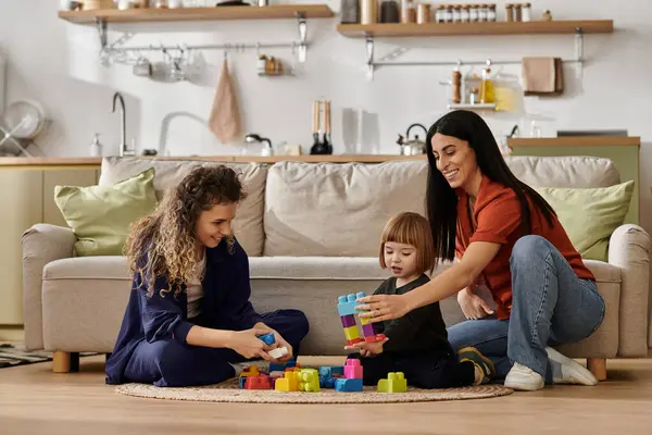 Two women joyfully engage with their daughter while playing with colorful building blocks. — Stock Photo