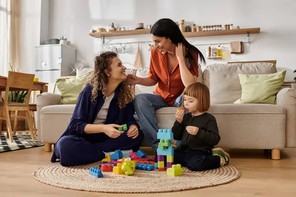 Two women share joyful moments as they play and bond with their young daughter at home. — Stock Photo