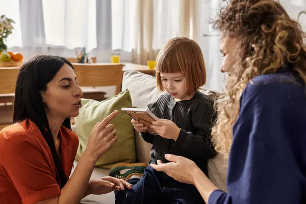 Two women joyfully engage with their young daughter in a stylish apartment setting. — Stock Photo