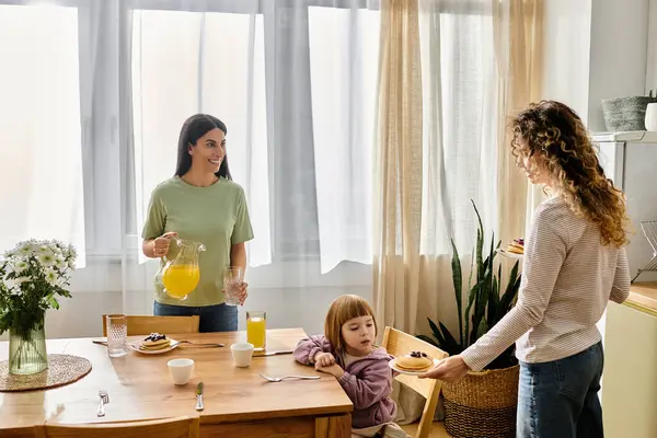 In un luminoso appartamento moderno, due donne godono la colazione con la loro figlia, favorendo la connessione. — Foto stock