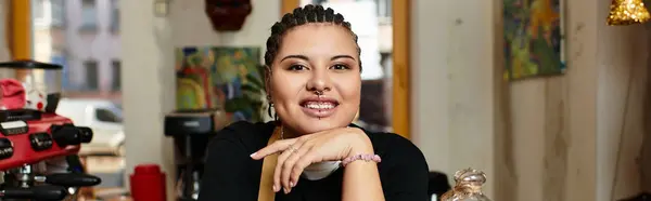 A confident young woman shares her smile as she interacts with patrons in a welcoming cafe setting. — Stock Photo