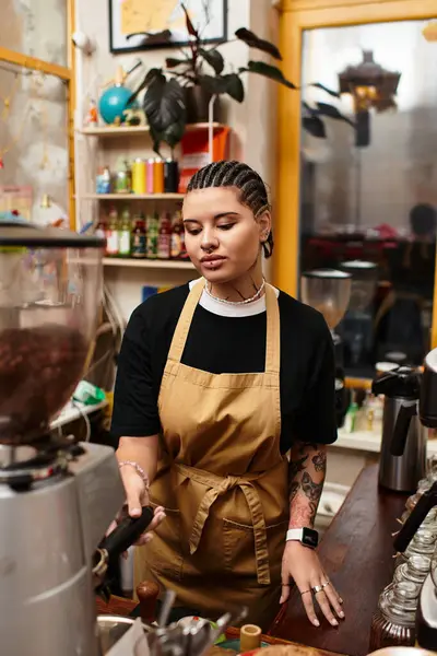 A young woman in an apron focuses on brewing a perfect cup of coffee in a lively cafe. — Stock Photo