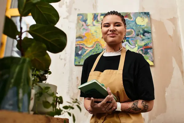 Smiling young woman stands in a cozy cafe, showcasing her personality while holding a notebook. — Stock Photo