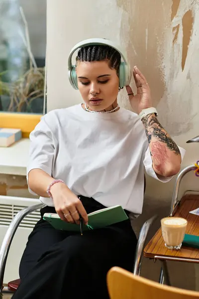A beautiful young woman immersed in her favorite tunes while jotting down thoughts at a cafe. — Stock Photo