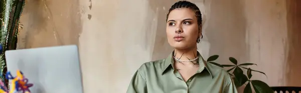 Une jeune femme s'assoit dans un café, réfléchissant avec son ordinateur portable dans une atmosphère chaleureuse. — Photo de stock