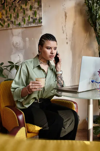 In a lively cafe, a young woman engages on a call while sipping coffee and focused on her laptop. — Stock Photo