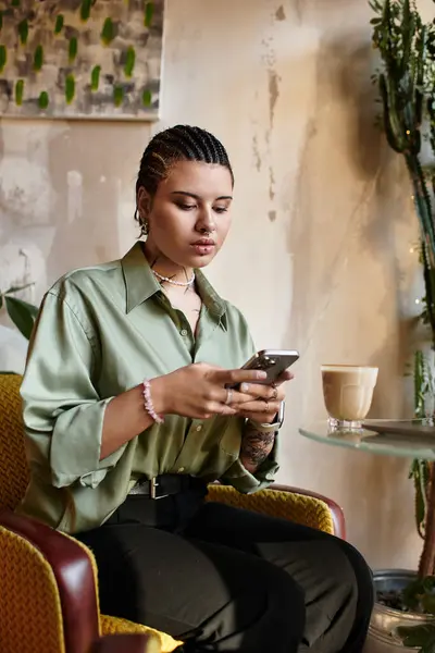 Charming young woman relaxes at a cafe while focused on her phone amidst a casual ambiance. — Stock Photo