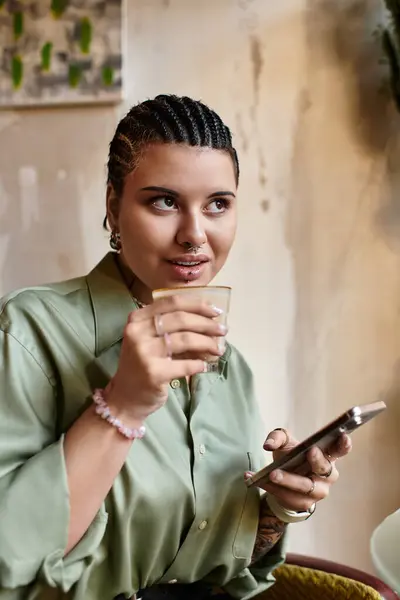 Relaxing in a cozy cafe, a young woman sips her drink and chats on her smartphone, radiating joy. — Stock Photo