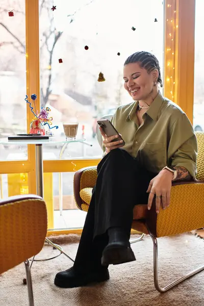 A young woman smiles at a stylish cafe, using her smartphone in a relaxed atmosphere. — Stock Photo