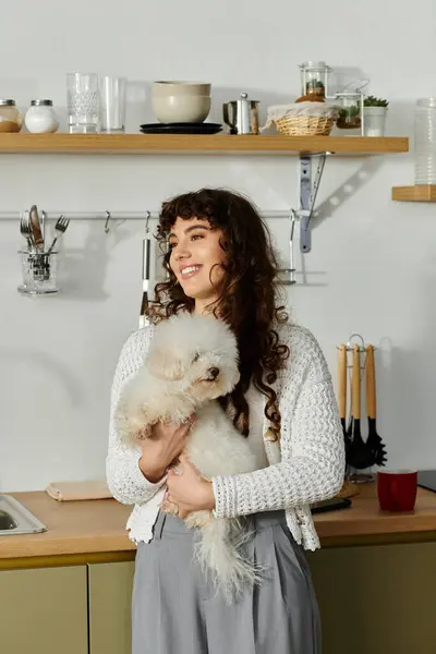 A cheerful woman cradles her dog in a stylish kitchen, filling the air with joy. — Stock Photo