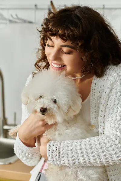 A young woman embraces her fluffy white dog while smiling in a warm and inviting space. — Stock Photo