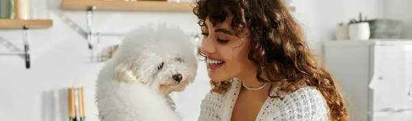 A young woman beams while holding a fluffy dog in a cozy room. — Stock Photo