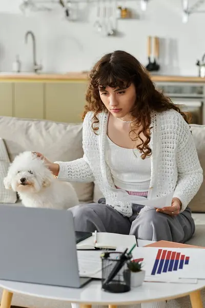 A young woman is deeply engaged in her work at home, sitting with her dog by her side. — Stock Photo