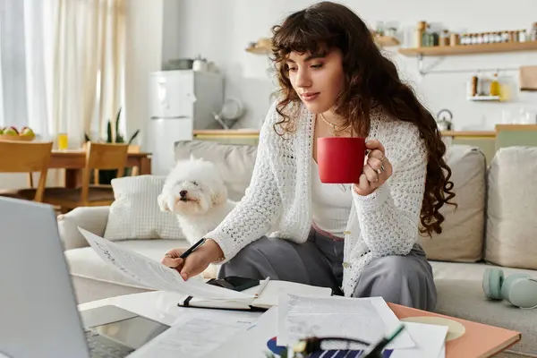 Giovane donna che si gode un caffè mentre studia a casa, circondata da un'atmosfera vivace. — Foto stock