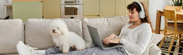 In a cozy living room, a woman works on her laptop while her dog relaxes beside her. — Stock Photo