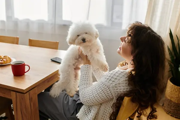 Embracing a warm moment, a young woman holds her fluffy white dog while savoring a peaceful morning. — Stock Photo