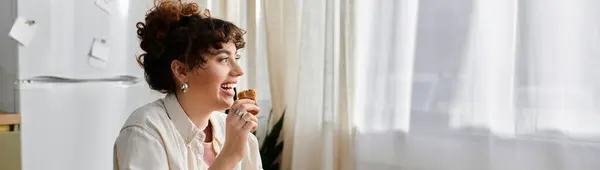A happy woman enjoys a delicious treat in her sunny, warm kitchen. — Stock Photo