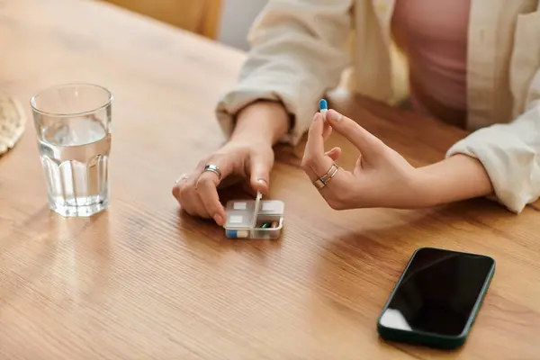 Uma jovem mulher em uma mesa rústica organiza sua medicação com foco cuidadoso. — Fotografia de Stock
