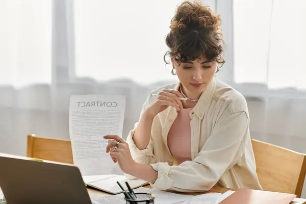 Une jeune femme étudie un contrat à une table en bois, perdu dans la concentration. — Photo de stock