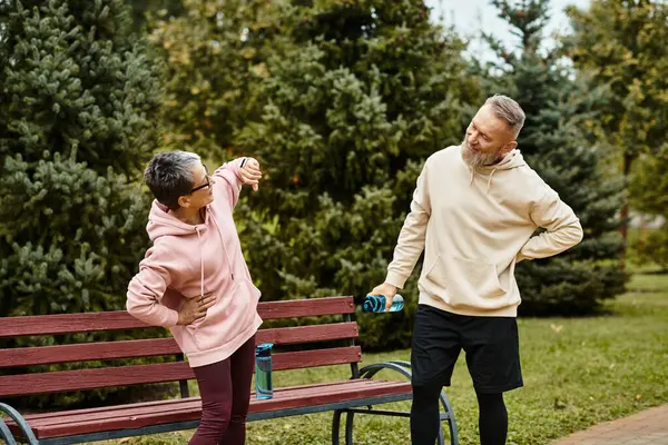 A loving couple shares laughter and joy while stretching in a vibrant park surrounded by greenery. — Stock Photo