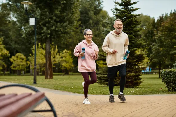 Loving couple enjoys a refreshing jog in a serene park surrounded by lush greenery. — Stock Photo