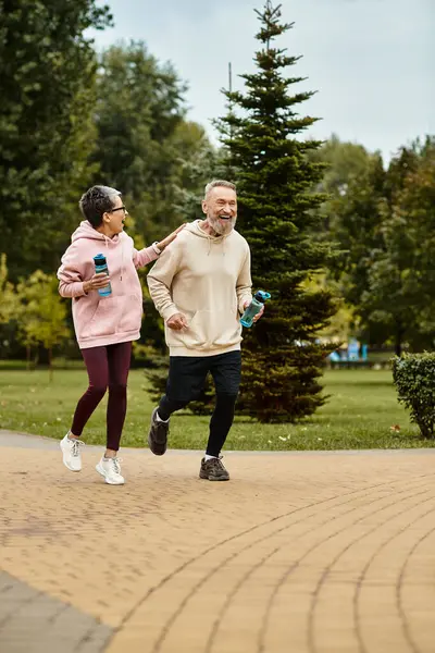 A loving couple experiences joy while jogging together in a serene park, surrounded by nature. — Stock Photo