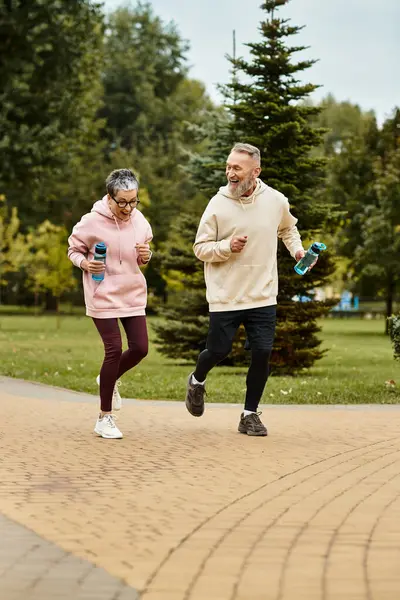 A loving couple is jogging through a green park, sharing laughter and joy together. — Stock Photo
