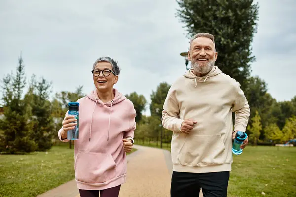 Joyful couple enjoys a morning jog through a vibrant park, savoring the fresh air and companionship. — Stock Photo